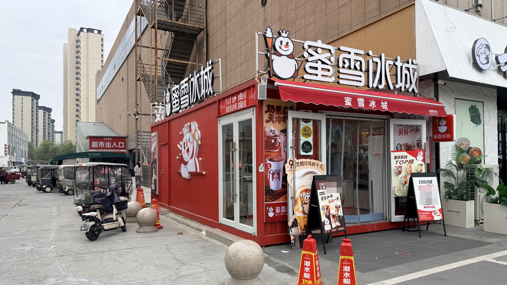开封兰考兰美广场蜜雪冰城集装箱奶茶店开业外观,可见红色箱体、品牌店招与玻璃门。