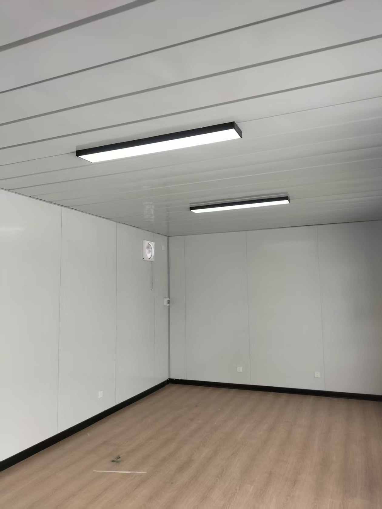 集装箱办公室简装室内地面与吊顶。室内实拍:木地板、白色吊顶瓦与条形照明,房间尚未布置办公家具。