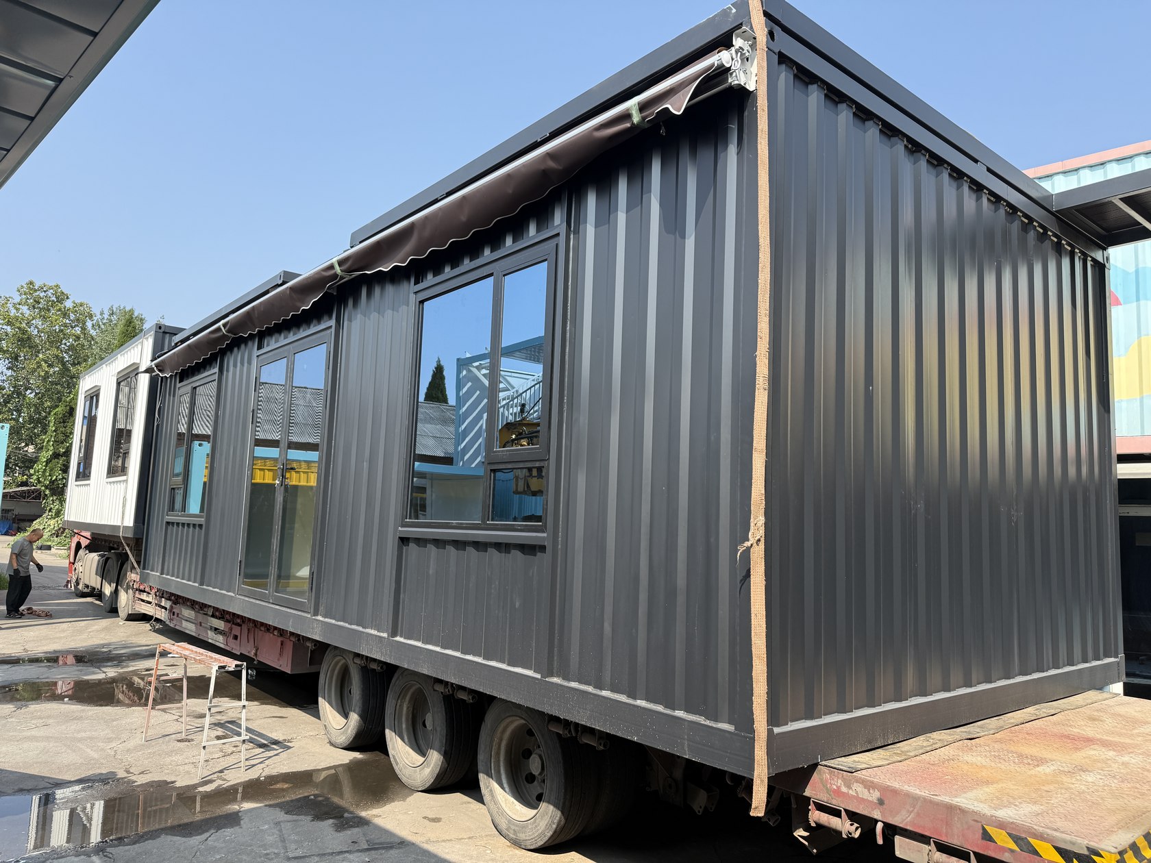 物流园集装箱办公室装车发运记录。装车照片:首层门窗与收起的遮阳棚已安装,箱体随车辆发运。