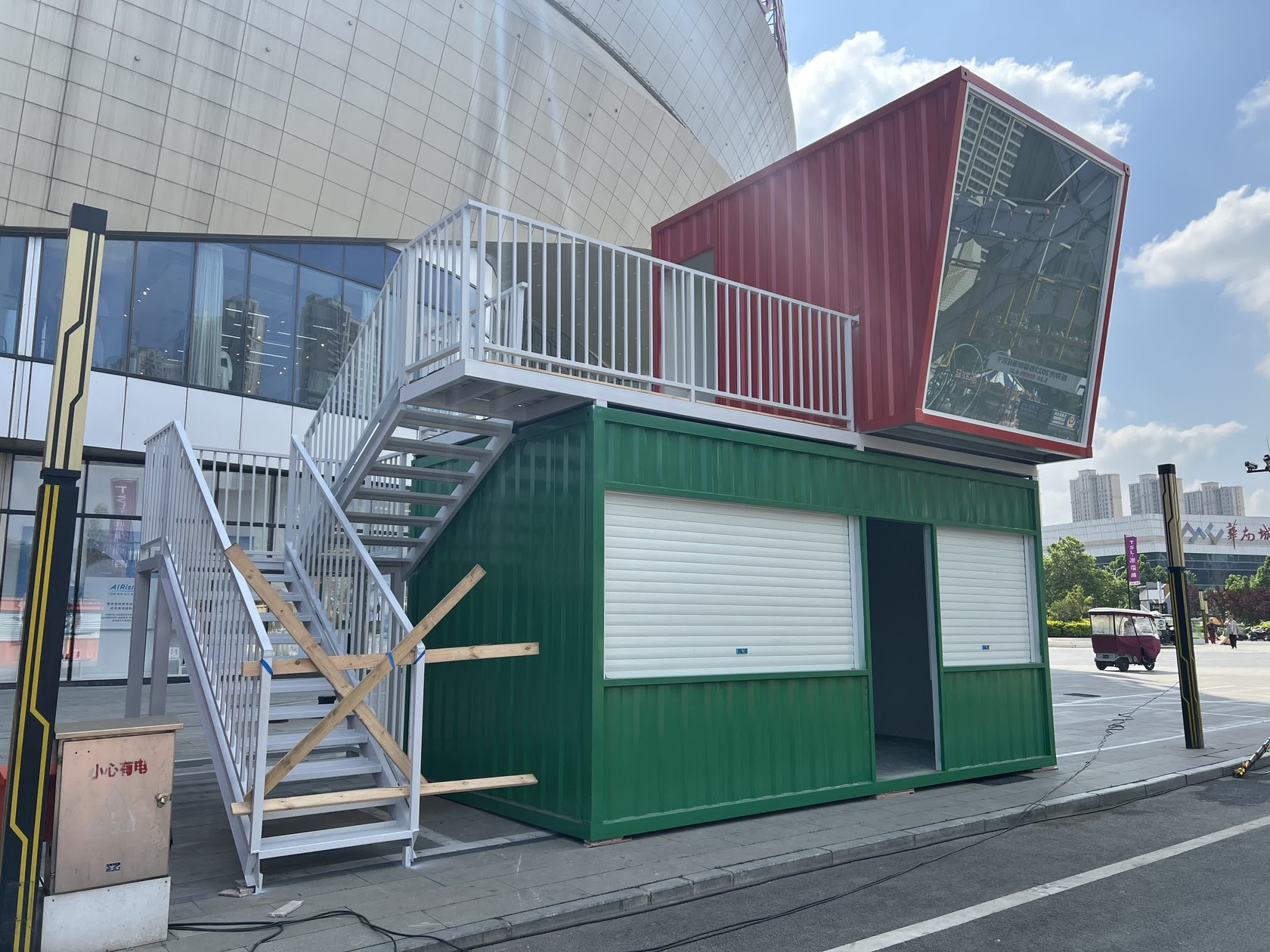 龙湖锦艺城附近两层集装箱啤酒屋安装后实拍,可见银灰色外置楼梯、平台栏杆、绿色一层与红色二层。