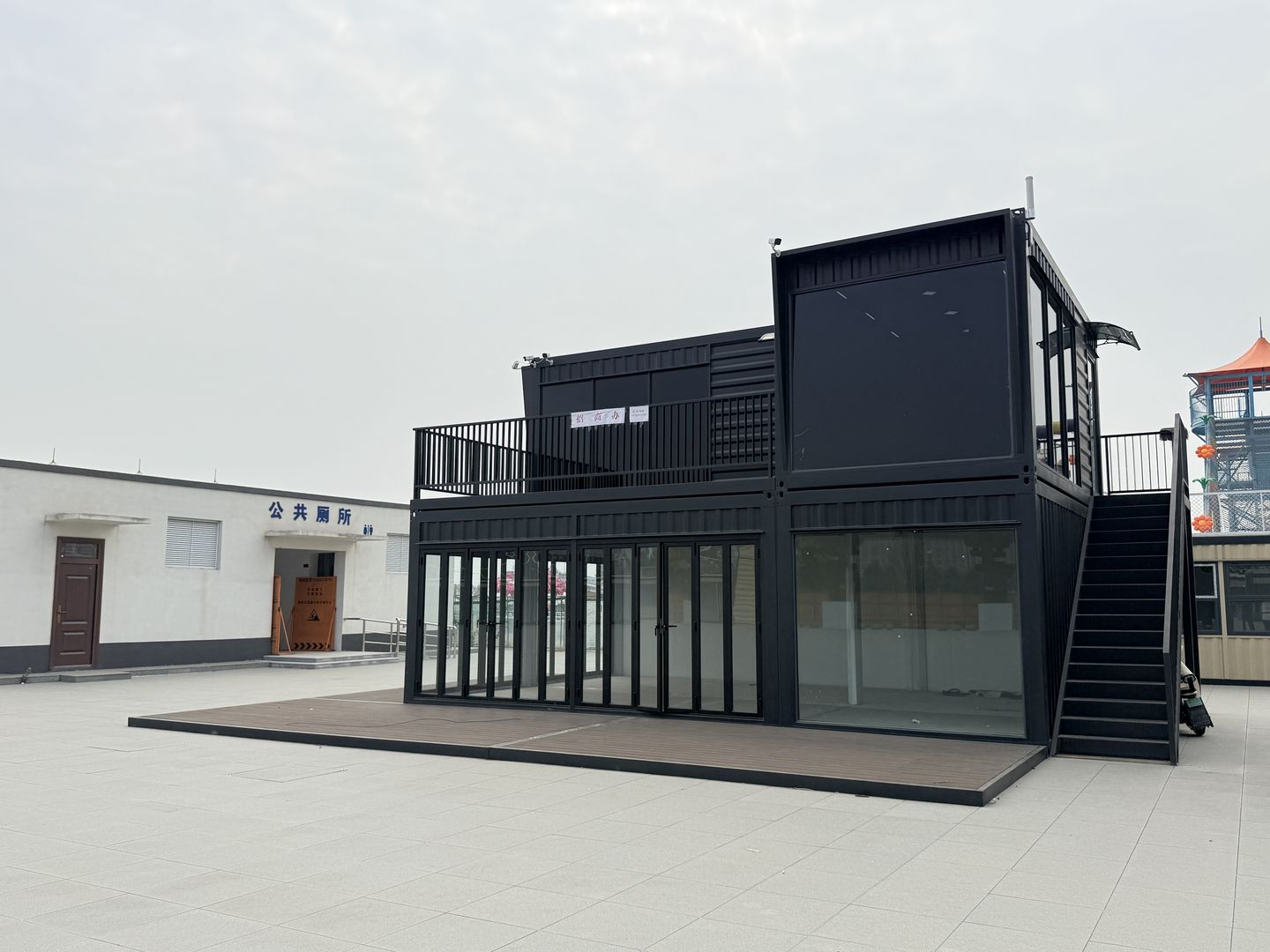 江苏徐州丰县大汉丰景深色双层商铺实景,完工实拍:深色框架、双层箱体与侧向楼梯组合。